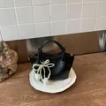 Elegante schwarze Handtasche mit Perlen-Tulpen-Anhänger auf weißen Tellern - Mit Anhänger-Stil / Schwarz