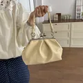 Elegant cream yellow pleated shell handbag with vintage metal clasp in a stylish room - Yellow