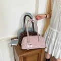 Stijvolle polkadot kussen schoudertassen in roze, bruin en blauw op een houten tafel. - Roze Met Hanger