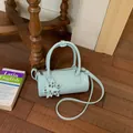 Elegant light blue woven cylinder handbag with a star charm and crossbody strap - Blue