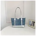 A front-view detail of a stylish denim tote bag featuring silver metallic accents and handles. - No Pendant / Silver