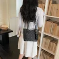 Elegant black commuter bucket bag with stylish monogram pattern shown on model in library - Without Pendant / Black