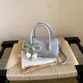 Stylish light blue textured pillow handbag featuring a decorative pearl bow charm detail - With Charm / Blue