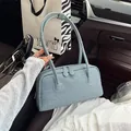 Fashionable blue denim textured Boston pillow bag for women shown in car interior setting - Light Blue