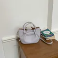 Elegant lilac pebbled leather bucket bag featuring top handles and crossbody strap - Purple
