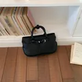 Elegant black pebbled leather handbag with top handle and buckle detail - Black