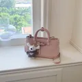 Pink textured leather handbag with cute plush bear pendant on windowsill - Pink With Pendant