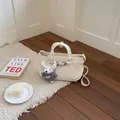 Elegant cream leather handbag with a cute white teddy bear charm accessory. - White With Pendant