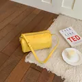 Vintage yellow cylinder shoulder bag on white rug in a cozy indoor setting with light - Yellow