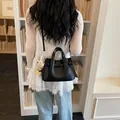 Elegante schwarze Handtasche aus genarbtem Leder mit süßem Bärenanhänger für den Büroalltag. - Schwarz