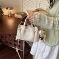 Elegante cremefarbene Leder-Einkaufstasche mit Knotendetails und süßem Teddybär-Anhänger. - Weiß