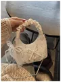 Gros plan d'un sac à main blanc à poignée plissée avec strass et petit nœud décoratif - Blanc Avec Pendentif