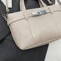 Beigefarbene Handtasche aus genarbtem Leder mit silbernem Drehverschluss und Schultergurt - Gebrochenes Weiß