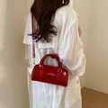 Elegant red glossy pillow handbag with detachable crossbody strap shown on a model - Without Pendant / Red
