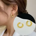 Detail of 18K gold plated titanium steel hoop earrings on model and white surface - French Vintage Thick Hoop Style (E13)