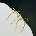 Close-up detail van elegante gouden strikoorbellen met lange slangenkettingkwastjes - Gouden Lange Kwast Strik Oorbellen (7194)