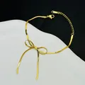 Detailopname van een gouden strikarmband met een slank slangenkettingontwerp - Gouden Strik Slangenketting Armband (5161)