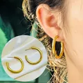 Detailed view of 18K gold plated stainless steel hoop earrings on model and fabric - Thick C-Shape Hoop Style (7644)