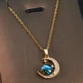 Close-up of golden crescent moon necklace with a blue nebula planet orb and zircons - Dreamy Star Moon