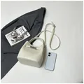 Bolso bombonera beige elegante con asa superior y bandolera en composición plana - Blanco