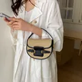 Chic woven straw saddle bag featuring black leather trim and decorative gold buckles - Black