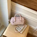 Elegant pink leather pillow bag with dual handles and crossbody strap on a wooden stool - Regular Fit / Pink