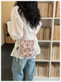Dettaglio borsa a tracolla stile cinese con ricami colorati su camicetta bianca. - Rosa
