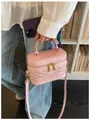 Petit sac à main rose structuré avec motif tressé tenu par une personne en tenue décontractée - Rose
