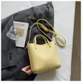 Elegant yellow pebbled leather bucket bag featuring top handles and adjustable strap - Yellow Without Charm