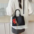 Elegant black faux leather bucket bag featuring a red horse charm and shoulder strap - With Pendant / Black
