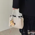 Elegant cream bucket bag featuring white knot handles and a playful horse charm variant - With Pendant / White