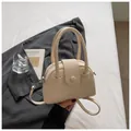 Detailweergave van beige kiezellederen handtas met ronde handvatten en riem - Alleen Tas / Wit