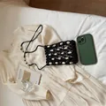 Bolso bandolera de verano tejido en negro con detalles de conchas sobre un vestido crema - Café