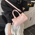 Elegant pink lychee grain leather handbag featuring top handles and crossbody strap - Pink