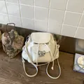 Elegant white sweet style backpack for women featuring a silver bow ornament and flap - White