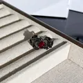 Primer plano detallado de un anillo gótico de espinas negras con piedra roja vibrante - Anillo Abierto Espina Fluida Gema Roja