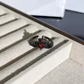 Vista macro detallada de un anillo de corona gótica negra con gema de corazón rojo - Anillo Abierto Corona Corazón Espinas