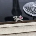 Nahaufnahme eines silbernen Schleifenrings mit funkelndem rosa Herzstein auf Display. - Rosa Herz-Zirkon-Schleife-Stil (Stil 18) / Silber