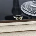 Detailansicht eines eleganten silbernen Schleifenrings mit grünen Edelsteinen und Kristallen - Hellgrüner Zirkon Pave-Schleifenstil (Stil 21) / Silber
