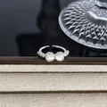 Eleganter silberner Schleifenring mit Diamanten und Perlen auf einem beigen Ständer. - Perlmutt Perle Schleife Stil (Stil 1) / Silber