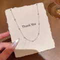 Close-up of a delicate pearl station necklace resting on a textured Thank You card. - Silver Necklace (X2224)
