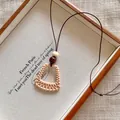 Macro view of the beige woven trapezoid pendant necklace with natural wood bead. - Woven Trapezoid Style (X2280B)