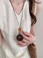 Elegant vintage brown donut pendant necklace on cord worn by model in linen top - Wooden Ring Style (X2281B)