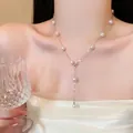 Detail of elegant Y-shaped silver necklace with white pearls worn by model in white dress. - Silver