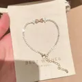 Close-up detail showing pink bow and flower zircon bracelet on a beige gift pouch. - Pink Heart Bowknot Style (S834金) / Gold