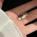 Elegantes Detail eines minimalistischen offenen Rings mit Perlen und Kristallen am Finger. - Silber