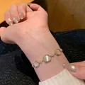 Close-up view of an elegant gold bracelet featuring cat's eye stones on a woman's wrist - Round Cat's Eye Stone Style (S839金) / Gold