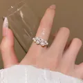 Detailed close-up of an elegant pearl and zircon cluster ring on a model's hand. - Clustered Pearl Open Ring (J1114)