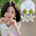 Detail of elegant white flower earrings with green studs on model and display card - Gold (E7008)