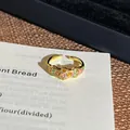 Detaillierte Nahaufnahme eines Vintage-Emaille-Rings mit Blume und rosa Edelstein auf Papier. - Stil 7 Offener Ring (6541588205)